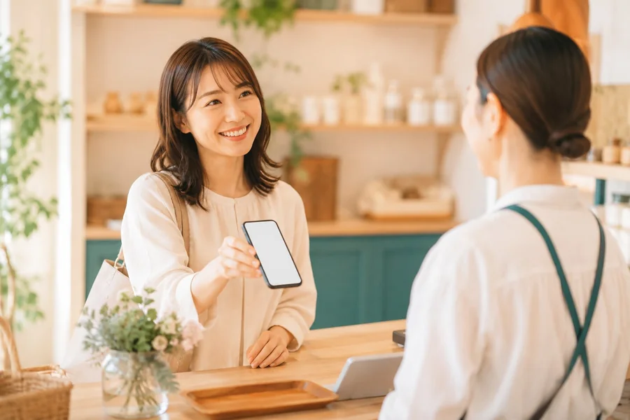 店舗でスマホのクーポンを提示するお客様のイメージ